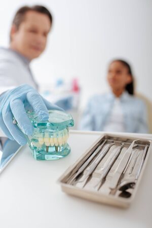 selective focus of dentist in latex glove taking teeth modelの写真素材