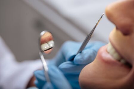 cropped view of dentist in latex gloves holding dental instruments near smiling man