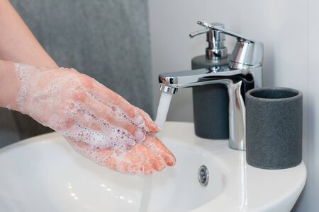 cropped view of young woman washing soapy hands in bathroomの写真素材