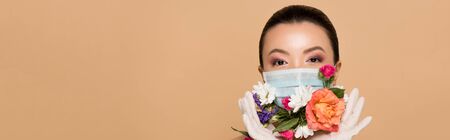 panoramic shot of asian girl in latex gloves and floral face mask isolated on beigeの写真素材