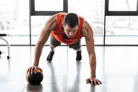 handsome sportsman doing plank exercising with ball