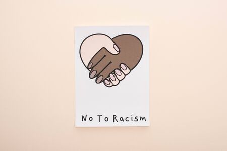 top view of picture with multiethnic handshake and no to racism lettering on beige backgroundの写真素材