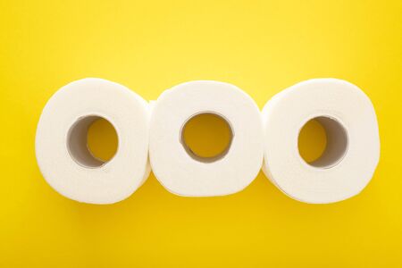 flat lay with white toilet paper rolls on yellow background