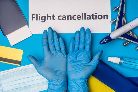 Top view of doctor in latex gloves near card with flight cancellation, toy plane with flag of...