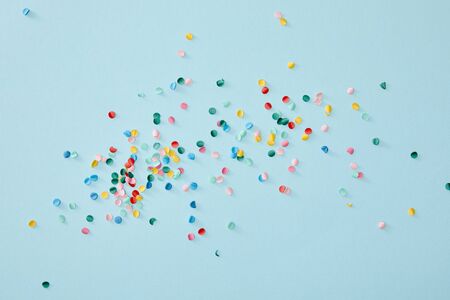 top view of colorful confetti scattered on blue background