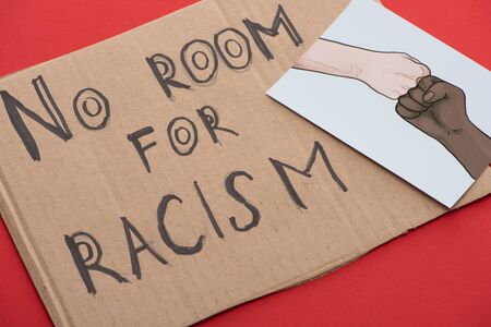 carton placard with say no room for racism lettering and picture with drawn multiethnic hands doing fist bump on red backgroundの写真素材