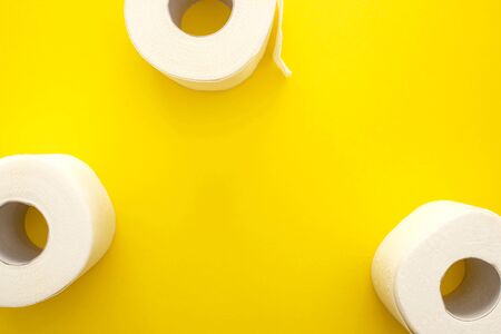 top view of white toilet paper rolls on yellow background with copy spaceの写真素材