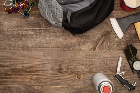 top view of backpack near hiking equipment on wooden surface