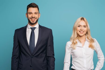 young, smiling couple of businesspeople looking at camera isolated on blueの写真素材