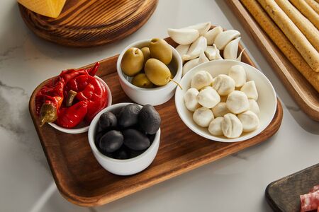 High angle view of boards with breadsticks, garlic and bowls with olives, mozzarella and marinated...
