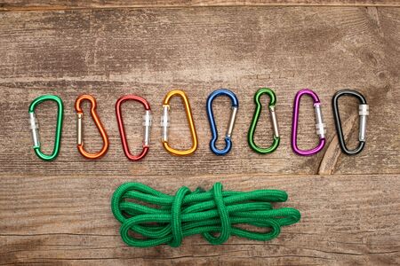 top view of colorful carabiners and green hiking rope on wooden tableの写真素材
