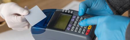 partial view of businessman holding credit card near delivery man with payment terminal, panoramic...