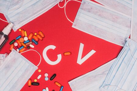 Top view of hand sanitizer, pills with medical masks and cv letters on red backgroundの写真素材