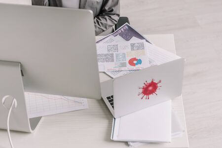 cropped view of businesswoman working at home near table with digital devices and documents