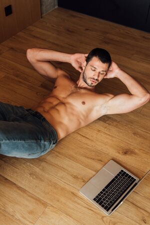 top view of muscular man exercising while watching online training on laptopの写真素材