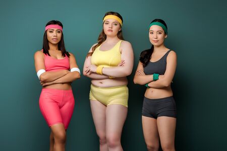 Sportswomen with crossed arms looking at camera on green backgroundの写真素材