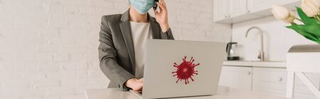 cropped view of businesswoman in medical mask talking on smartphone near laptop with coronavirus...