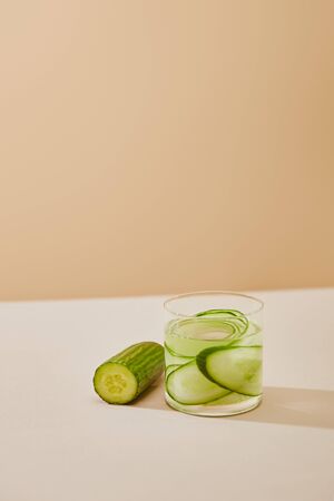 high angle view of glass of water with sliced cucumbers on table isolated on beigeの写真素材