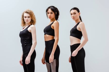 beautiful and multicultural women in sportswear standing isolated on whiteの写真素材
