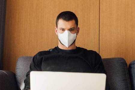 blogger in medical mask using laptop at homeの写真素材