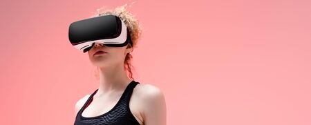 panoramic shot of woman in in sportswear and virtual reality headset on pink