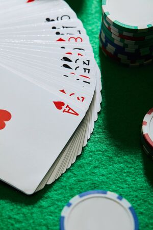 high angle view of playing cards with casino chips on green