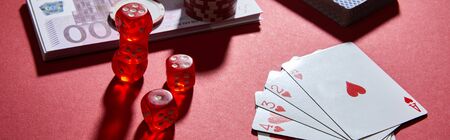 high angle view of playing cards, dice and money on red, panoramic shotの写真素材