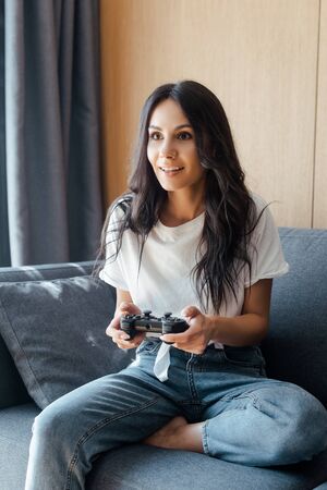 KYIV, UKRAINE - APRIL 9, 2020: attractive woman playing video game with joystick on self isolation