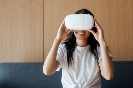 smiling young woman using virtual reality headset at home
