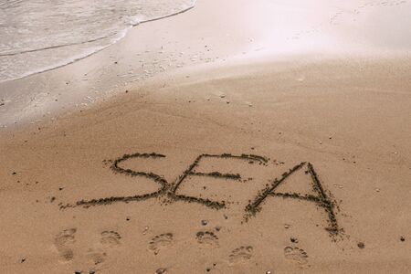 summer beach with sea lettering on sand