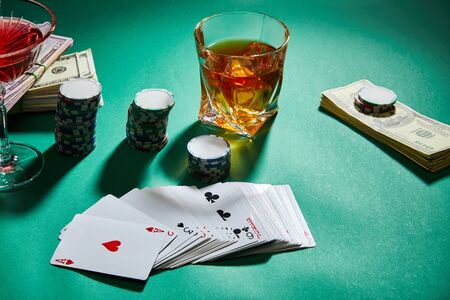 high angle view of glasses of cognac and cocktail with money, casino chips and playing cards on...