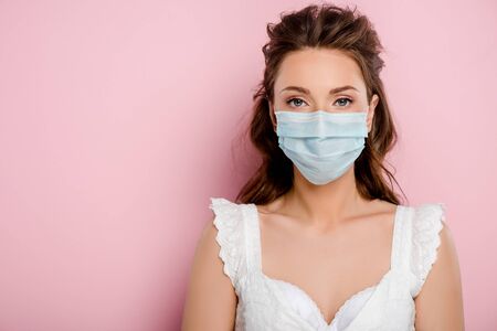 young woman in medical mask standing on pinkの写真素材