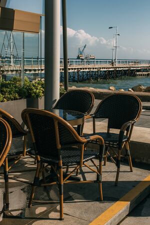 sunshine on chairs near table in summer terrace of restaurant near seaの写真素材