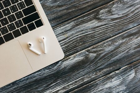top view of laptop and earphones on dark wooden surface