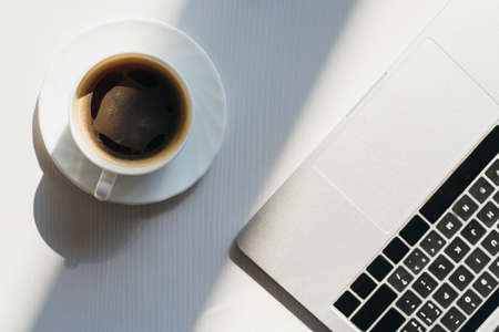 top view of empty workplace with laptop and cup of coffee in sunlight