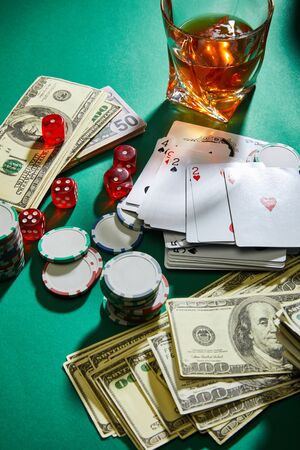 high angle view of money, playing cards, dice and casino tokens near glass of cognac on greenの写真素材