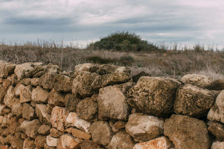 wall with stones near lawn against sky with clouds