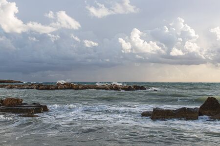 rocks near mediterranean sea against sky with clouds