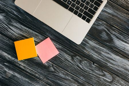 top view of laptop and sticky notes on dark wooden surfaceの写真素材