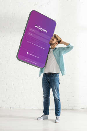 KYIV, UKRAINE - FEBRUARY 21, 2020: Thoughtful man holding model of smartphone with instagram appのeditorial素材