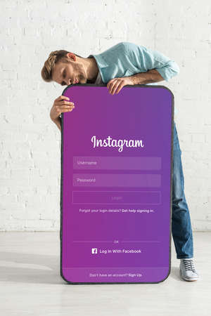 KYIV, UKRAINE - FEBRUARY 21, 2020: Handsome man kissing big model of smartphone with instagram appのeditorial素材
