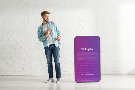 KYIV, UKRAINE - FEBRUARY 21, 2020: Confused man looking at big model of smartphone with instagram appのeditorial素材