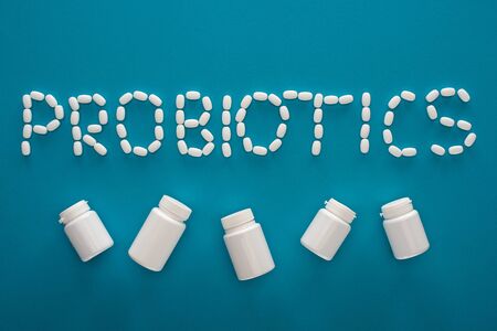 top view of probiotics lettering made of pills and white containers on blue backgroundの写真素材