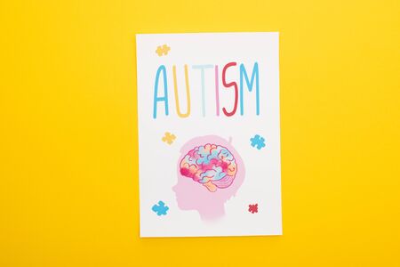 top view of paper sheet with autism lettering and drawing of child isolated on yellow