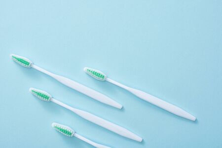 Flat lay with toothbrushes with green bristles on blue background