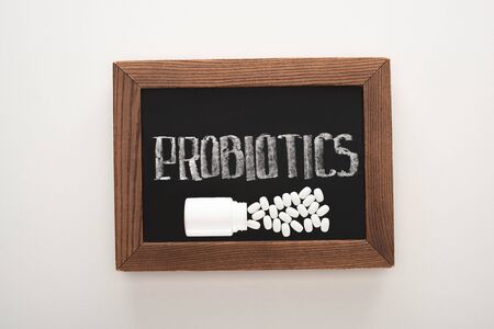 top view of chalkboard with probiotics lettering with pills and container on white backgroundの写真素材