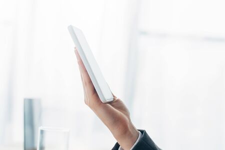 Cropped view of man holding smartphone with blank screen in hand