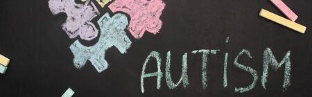 panoramic shot of chalkboard with word autism and puzzle drawingの写真素材