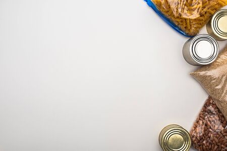 top view of cans and groats in zipper bags on white background, food donation concept