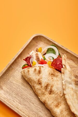 fresh burrito with chicken and vegetables on board on orange backgroundの写真素材